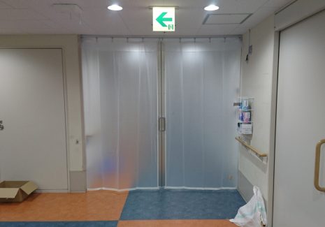 コロナ感染症対策として病院の通路を半透明ビニールカーテンで間仕切り