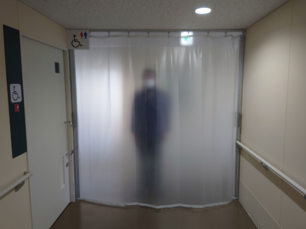 病院内の感染症対策に通路を区分けするため、プライバシーにも配慮した半透明ビニールカーテンを設置