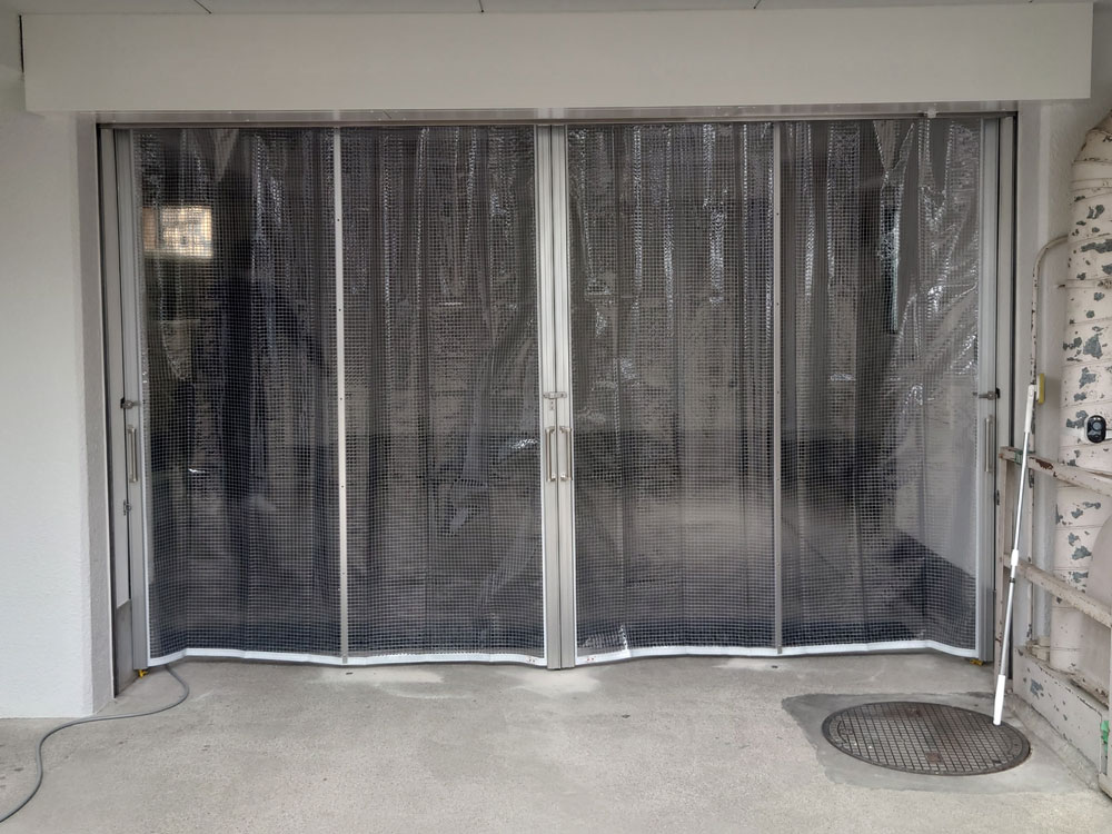 会社の駐車場出入口に埃よけ・防寒のための糸入り透明ビニールカーテンを設置