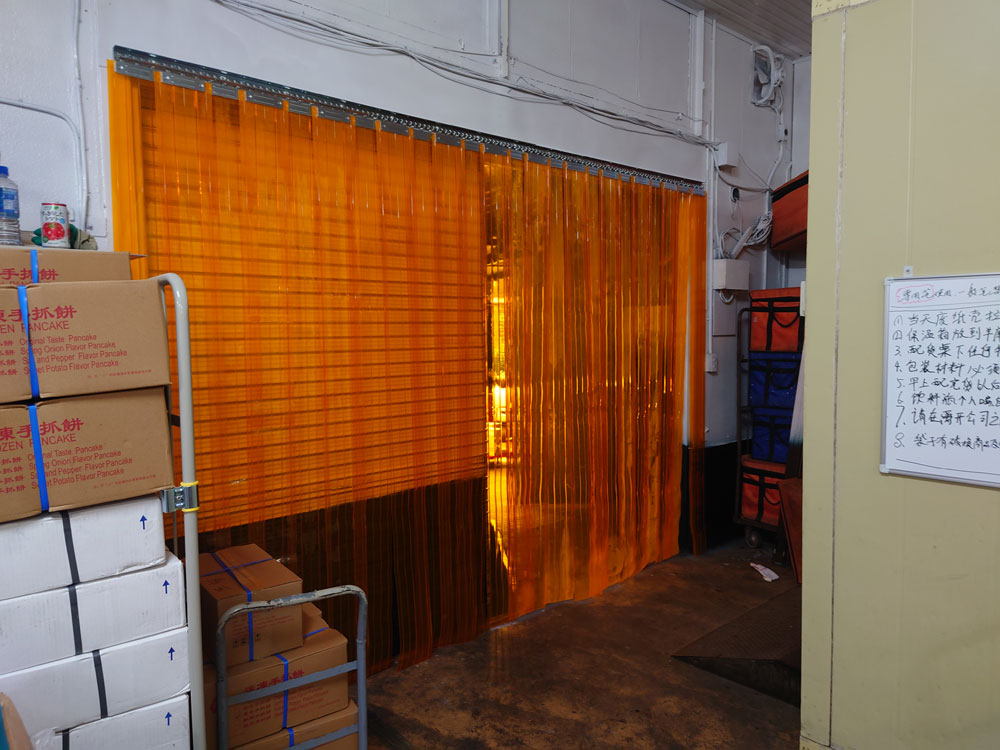 食品工場の出入口に省エネ対策のため防虫オレンジのリブ付きのれんカーテンを設置しました
