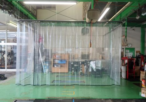 タイヤ販売店の自動車整備スペースにブース状に糸入り透明ビニールカーテンを設置