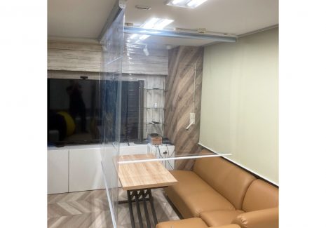 ショップ内の接客用ソファとテーブルをT字に仕切る形で飛沫感染対策用の電動透明ロールカーテンを設置していただきました