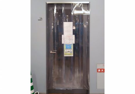 ホテルの喫煙室出入口に、改正健康増進法の基準に基づく流入風を得るための透明ビニールのれんカーテンを設置